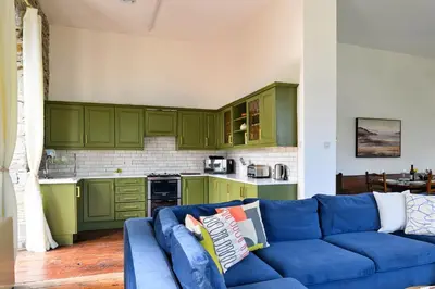 a blue couch in a kitchen with green cabinets at Finest Retreats - Luxury Converted Chapel with Hot Tub & Games Room in Dinas Mawddwy