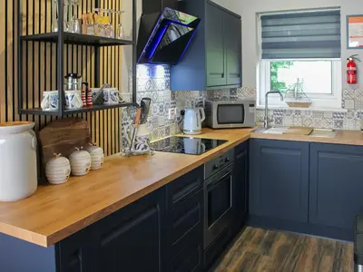 a kitchen with blue cabinets and a wooden counter top at Tyglyn Cottage in Lampeter