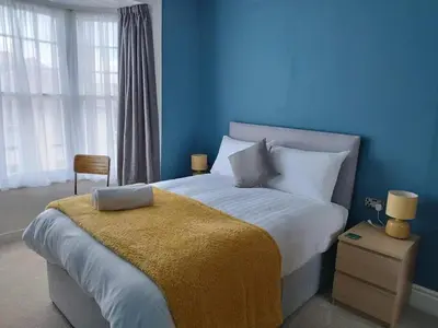 a blue bedroom with a large bed with a yellow blanket at Apartment 2, Aberystwyth Town Centre in Aberystwyth