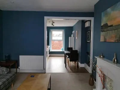 a living room with a blue wall and a table at Apartment 2, Aberystwyth Town Centre in Aberystwyth