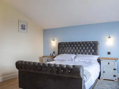 a bedroom with a large bed with a leather headboard at The Lookout - Uk35022 in Hope under Dinmore