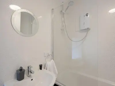 a white bathroom with a shower and a sink at Y Bwthyn in Llanrhystyd
