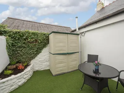 a patio with a table and chairs and a building at Y Bwthyn in Llanrhystyd