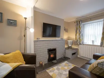 a living room with a fireplace and a tv at Y Bwthyn in Llanrhystyd