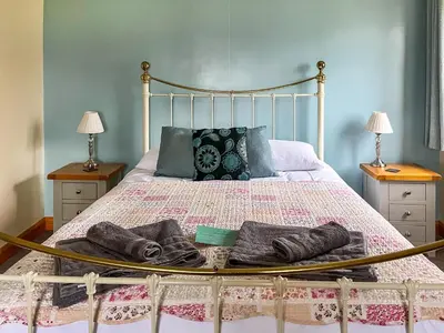 a bed with two pairs of slippers on it at The Larches in Hopton Cangeford