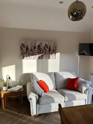 a living room with a gray couch and red pillows at Mini haven in Oswestry