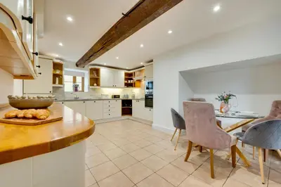 a kitchen with white cabinets and a table and chairs at 3 Bed in Machynlleth oc-bow321 in Cemmaes