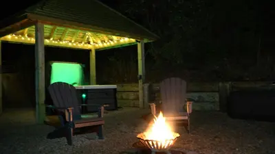 two chairs and a fire in a yard at night at Little Acorn - Luxury shepherd's hut / lodge with private hot tub and garden in Llanfyllin