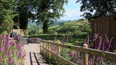 a garden with purple flowers and a fence at Little Acorn - Luxury shepherd's hut / lodge with private hot tub and garden in Llanfyllin