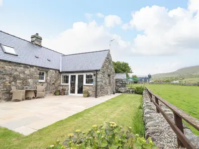 an exterior view of a stone cottage with a garden at Caerffynon Bach in Dyffryn