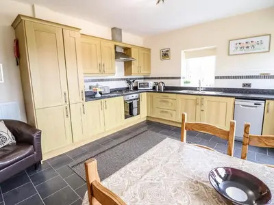 a kitchen with wooden cabinets and a table and a couch at Caerffynon Bach in Dyffryn
