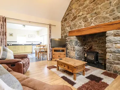 a living room with a large stone fireplace at Caerffynon Bach in Dyffryn