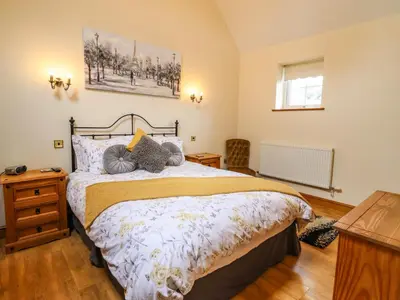 a bedroom with a bed and a wooden floor at Caerffynon Bach in Dyffryn