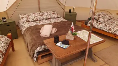 a room with a bed and a table in a tent at Calon Y Goedwig Glamping in Llandovery