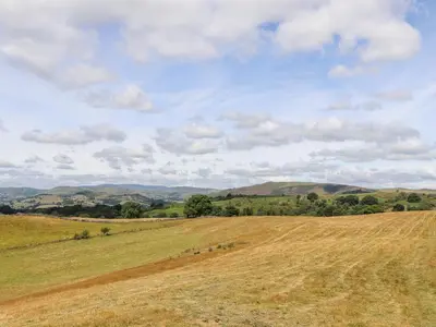 a field of brown grass with hills in the background at The Moorhen Retreat in Oswestry
