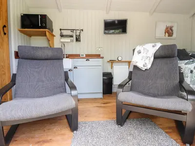 two chairs in a room with a kitchen and a bed at The Moorhen Retreat in Oswestry