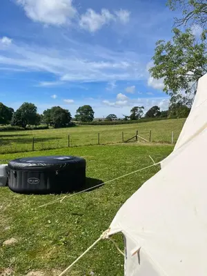 a tent sitting in the grass with a field at Tipi - Pengarreg in Aberystwyth