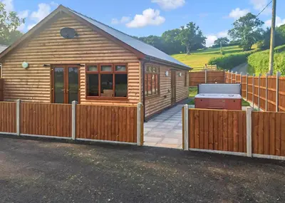 a wooden cabin with a fence in front of it at Heart Of Wales Lodges in Penybont
