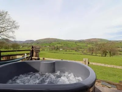 a bath tub filled with water next to a field at The Retreat in Oswestry