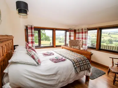 a bedroom with a bed and a chair and windows at The Retreat in Oswestry