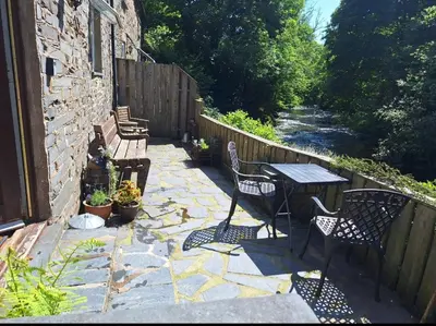 a patio with a table and chairs on a stone patio at Cosy riverside cottage in beautiful Corris in Corris