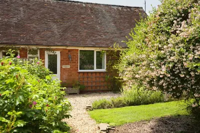 a small brick house with flowers in front of it at Woodpecker Way at Eaton Manor in Eaton