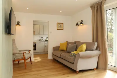a living room with a couch and a kitchen at Woodpecker Way at Eaton Manor in Eaton