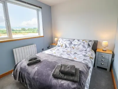 a bedroom with a bed and two windows at Bryn Hyfryd in Talsarnau