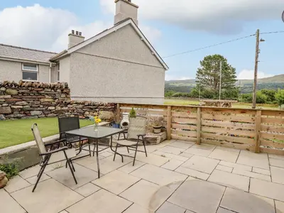 a patio with a table and chairs and a fence at Bryn Hyfryd in Talsarnau