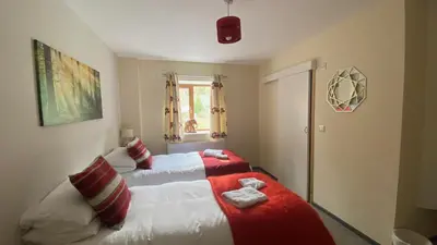a bedroom with a bed with a red and white blanket at MotoCamp Wales - Lodges in Dolgellau