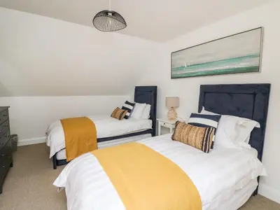 a bedroom with two beds and a painting on the wall at Ty Ni in New Quay