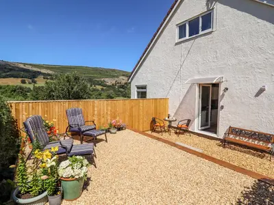 a backyard with two chairs and a fence at Cam O'r Fechan Annexe in Llangollen