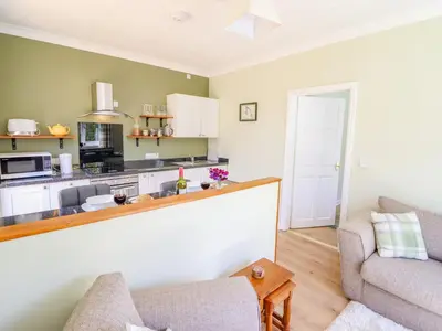 a living room with a couch and a kitchen at Cam O'r Fechan Annexe in Llangollen