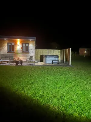 a house with a backyard at night with a lawn at MAESLLAN CABINS - 'Golwg Y Mor' in Cross Inn