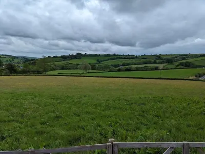 a field of green grass with a wooden fence at Top of the Rock Glamping in Trefeglwys