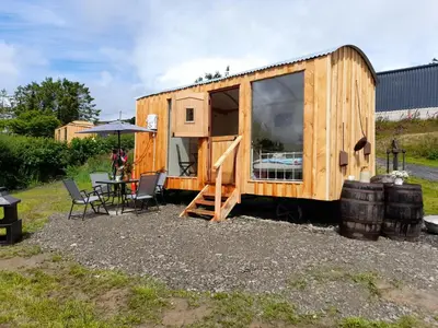 a wooden tiny house with a table and chairs at Top of the Rock Glamping in Trefeglwys