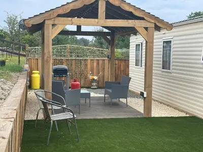 a wooden pergola with chairs and a table at Pant yr onen holidays in Llandrindod Wells