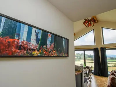 a large tv hanging on a wall in a living room at Llety Cariad in Montgomery