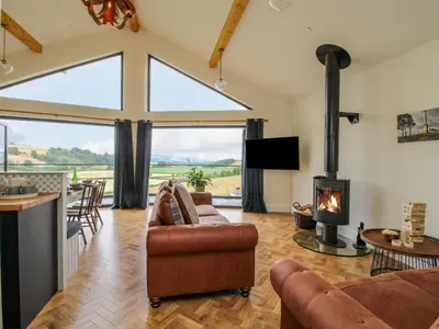 a living room with a fireplace and a large window at Llety Cariad in Montgomery