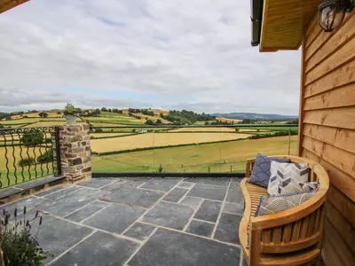 a patio with a bench and a view of the fields at Llety Cariad in Montgomery