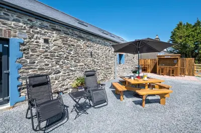a patio with a table and chairs and an umbrella at 4 Bed in Aberystwyth oc-bow304 in Rhostie