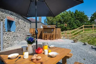 a wooden table with an umbrella on a patio at 4 Bed in Aberystwyth oc-bow304 in Rhostie