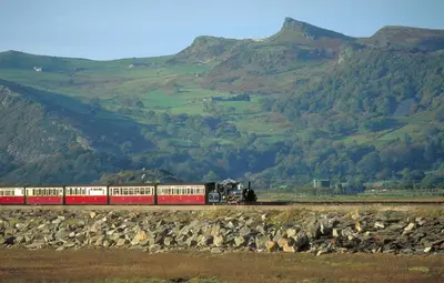 a red and white train on the tracks near mountains at 3 Bed in Trawsfynydd oc-wag718 in Trawsfynydd