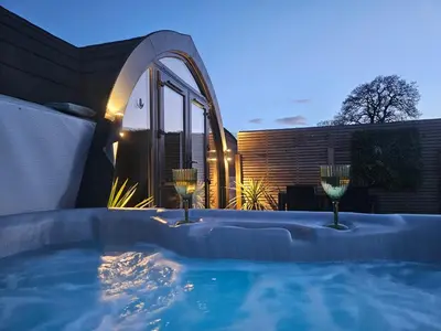 a hot tub in a backyard with two wine glasses at EASTRIDGE GLAMPING in Shrewsbury
