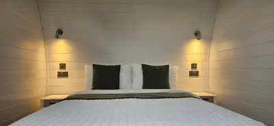 a bedroom with a bed with white sheets and pillows at EASTRIDGE GLAMPING in Shrewsbury