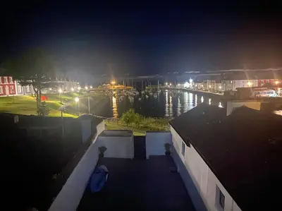 a view of a city at night with a body of water at Aberaeron Island House - Panoramic Harbour Views in Aberaeron