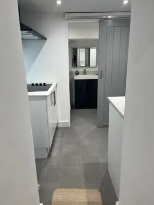 a kitchen with white cabinets and a tile floor at Harbour Apartment in Barmouth