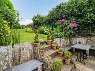 a garden with a bench and a table and flowers at Preswylfa in Blaenau-Ffestiniog