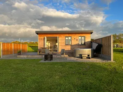 a small house with a patio in a yard at MAESLLAN CABINS 'Hud Y Machlud' in Cross Inn