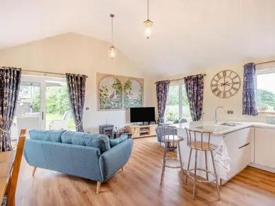 a living room with a blue couch and a kitchen at Violet Cottage in Hereford